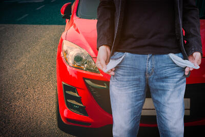 Man showing his empty pockets with red car parked on the street.