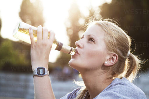young woman drinking beer of a bottle FEXF000030