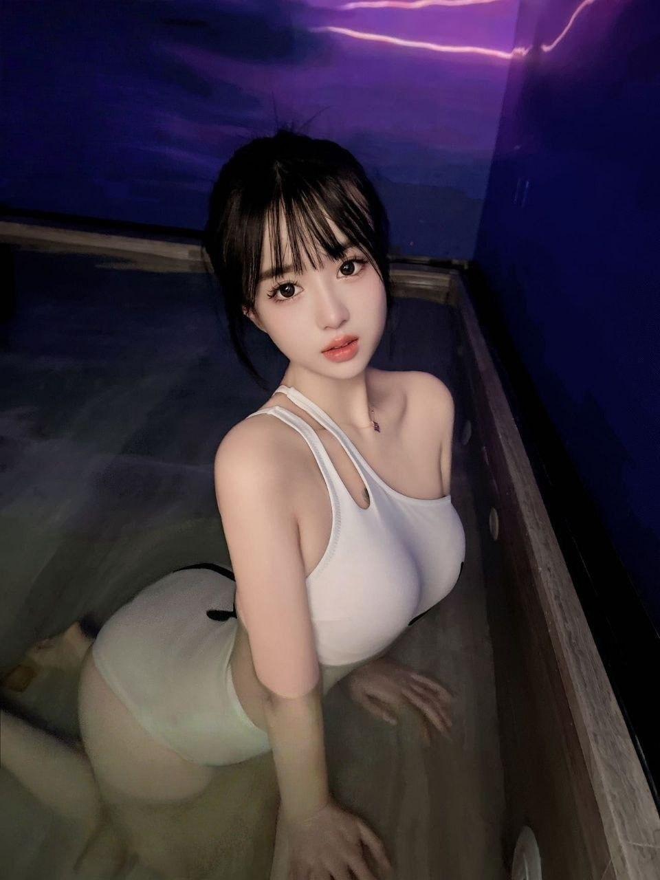特寫一位女性側臉，她閉著眼睛，嘴角帶著滿足的微笑，臉頰微紅。手輕輕扶著額頭，展現出剛經歷過聲音顫抖高峰後的慵懶與真實感。